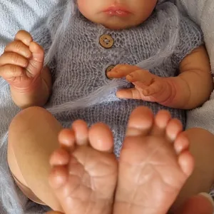 Lifelike 18 inch Reborn Baby Doll Jude wearing a grey knit sweater on plush fabric