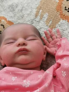 Close-up of lifelike 20 inch reborn doll showing detailed 3D skin and floral outfit