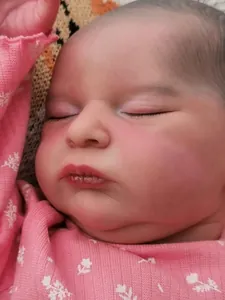 Close-up of lifelike newborn doll with 3D skin texture and veins in pink outfit