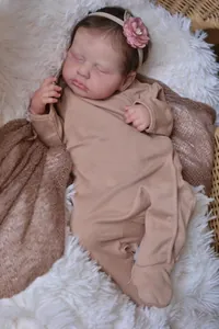 Detailed view of sleeping 19 inch reborn doll in romper resting in a wicker basket