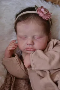 Close-up of 19 inch sleeping reborn doll Loulou with detailed skin and pink headband