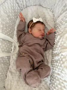 Close-up of 19-inch reborn doll in mauve knit romper sleeping on white bubble minky fabric