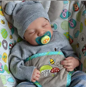 Close-up of sleeping reborn baby doll wearing a gray knit hat and mushroom bib