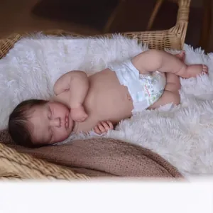 Lifelike 19-inch reborn baby doll Loulou sleeping in a cozy basket on plush white mat