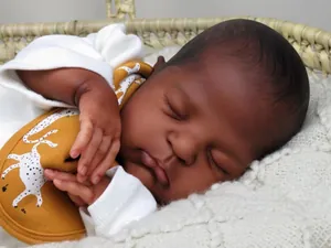 Gros plan d'une poupée reborn noire réaliste avec veines endormie dans un panier tissé