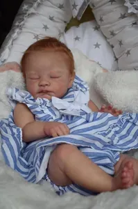 Macro detail of August reborn baby doll sleeping in blue striped romper on white fur