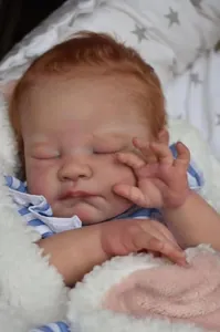 Close-up of sleeping reborn baby doll with detailed hand-rooted hair and soft skin