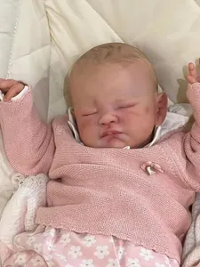 Gros plan d'une poupée reborn de 19 pouces dormant en gilet rose et robe à fleurs