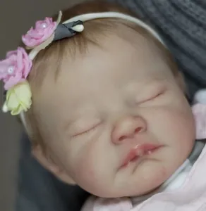 Close-up of sleeping reborn doll face with rooted hair and floral headband detail