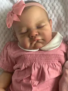 Gros plan d'une poupée reborn endormie en robe rose sur couverture blanche