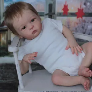 Poupée bébé reborn réaliste 55cm en body blanc en coton assise sur une chaise vintage blanche