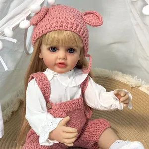 Κούκλα Reborn Betty με ροζ πλεκτά ρούχα καθισμένη σε μια άνετη σκηνή παιχνιδιού