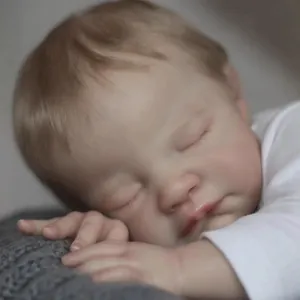 Lifelike 19-inch reborn baby doll August in sleeping pose with realistic skin and white outfit