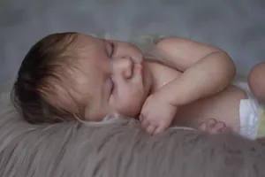 Close-up of sleeping reborn doll with realistic rooted hair and skin texture