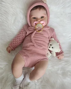 Détail de la poupée Maddie Reborn avec tenue en tricot rose, sucette coeur et petit ours