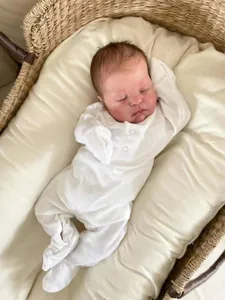 Close-up of white long-sleeve footed baby onesie with snap buttons on a newborn doll