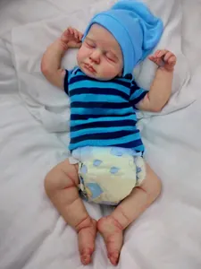 Macro shot of 49cm reborn baby doll sleeping in blue striped outfit and knit hat