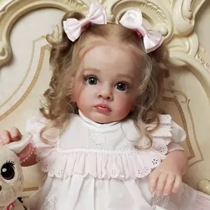 Detailed close-up of reborn baby doll with blonde curls, lace dress and plush toy