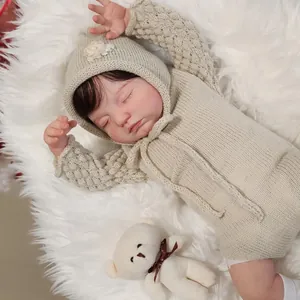Realistic sleeping reborn doll in beige knit bodysuit on white plush rug