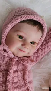 Gros plan de poupée bébé réaliste avec yeux verts et sweat à capuche rose tricoté