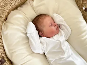 Close-up of white cotton newborn romper with button front and fold-over sleeve cuffs