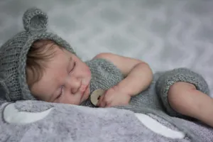 Close-up of 19 inch reborn doll wearing grey knitted outfit with wooden buttons