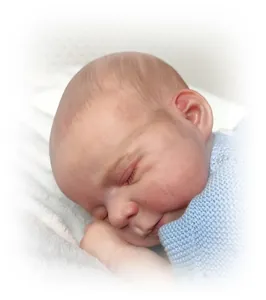 Close-up of a 48cm lifelike reborn baby doll sleeping with delicate skin and blue knitwear