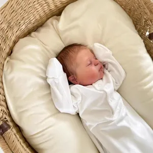 Realistic 49cm newborn baby doll Demi in white cotton bodysuit in a woven cradle