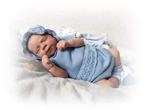 Close-up of sleeping reborn baby doll skin texture and blue knitted outfit details