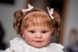 Close-up of Maddie reborn baby doll face with blue eyes and brown curly pigtails