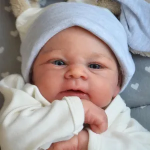 Poupée reborn réaliste de 49 cm avec yeux bleus et bonnet en tricot bleu en gros plan