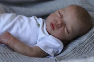 Close-up of sleeping 48cm reborn baby doll with realistic skin and white cotton bodysuit