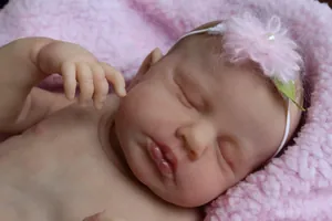 Close-up of a sleeping 49cm reborn baby doll with realistic skin texture and flower headband