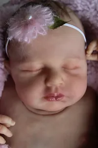 Close-up of lifelike reborn baby doll face with detailed skin texture and floral headband