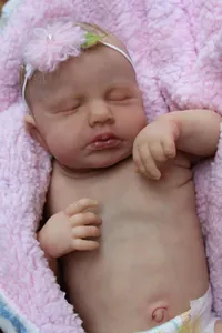 Close-up of sleeping reborn baby doll with realistic skin textures and a floral headband