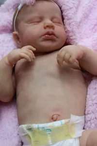 Close-up of realistic 49cm newborn doll skin textures and soft pink blanket detail