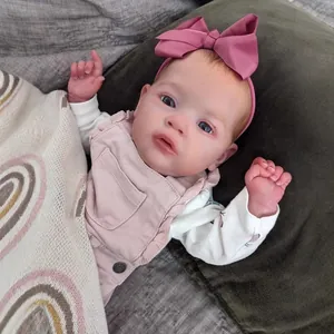 Lifelike 55cm reborn baby doll with blue eyes lying on velvet cushion and rainbow blanket
