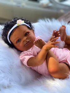 Detalle de muñeca reborn realista de piel oscura con pelo rizado y mameluco rosa