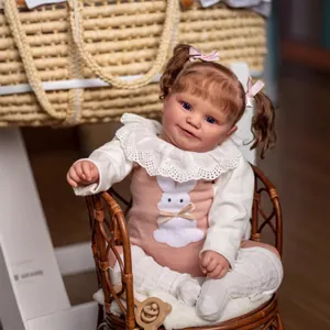Lifelike 60cm Maddie reborn baby girl doll in pink rabbit dress sitting on wicker chair