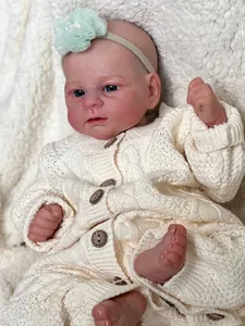 46cm Elijah reborn baby doll wearing a cream knit romper and lace flower headband