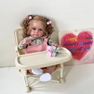 Poupée Reborn Tutti de 60 cm très réaliste avec cheveux bouclés assise sur une chaise haute