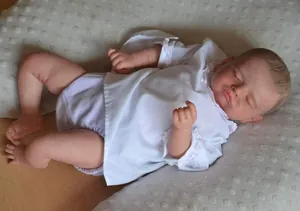 Detailed close-up of a realistic sleeping reborn baby doll with lifelike skin and lace outfit