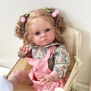 Poupée Reborn réaliste de 60cm avec boucles blondes et tenue à fleurs sur chaise