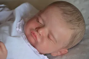 Close-up of sleeping Rosalie reborn doll showing realistic 3D skin texture and facial details