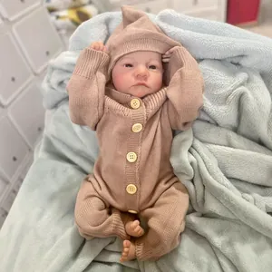 Realistic 49cm reborn baby doll Levi wearing a brown knitted romper on a blue plush rug