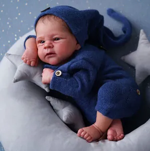Poupée nouveau-né 49cm à peau foncée avec tenue en tricot bleu marine et oreiller lune