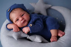 Poupée bébé reborn Elijah réaliste en tenue tricotée bleu marine sur coussin lune