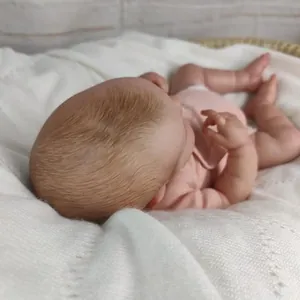 Realistic sleeping reborn baby doll in pink clothes lying in a cozy woven basket