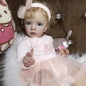 Realistic reborn baby doll Missy with blonde curls and pink outfit on plush background