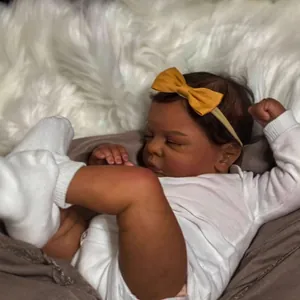 Realistic 49cm reborn baby doll with 3D skin texture in white romper and yellow bow